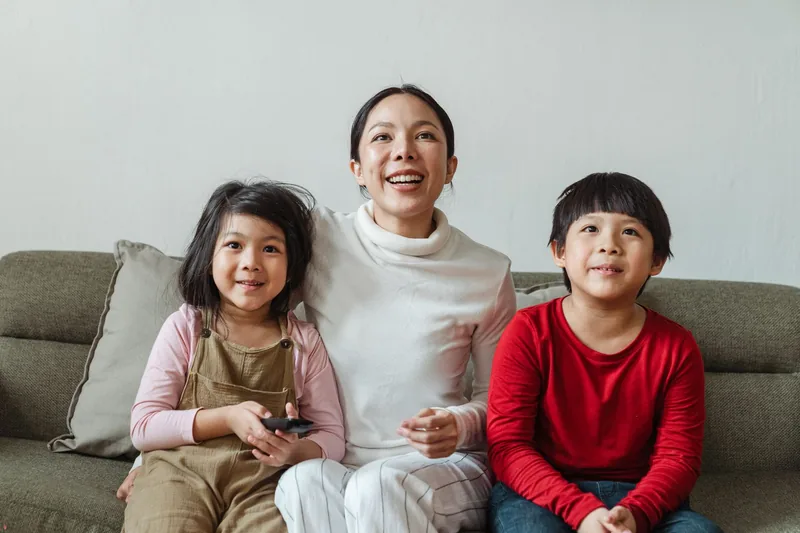 A parent and two children watching television at home