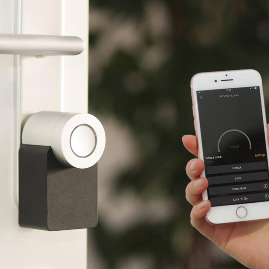 A phone showing a smart-lock app, held beside the lock on a door