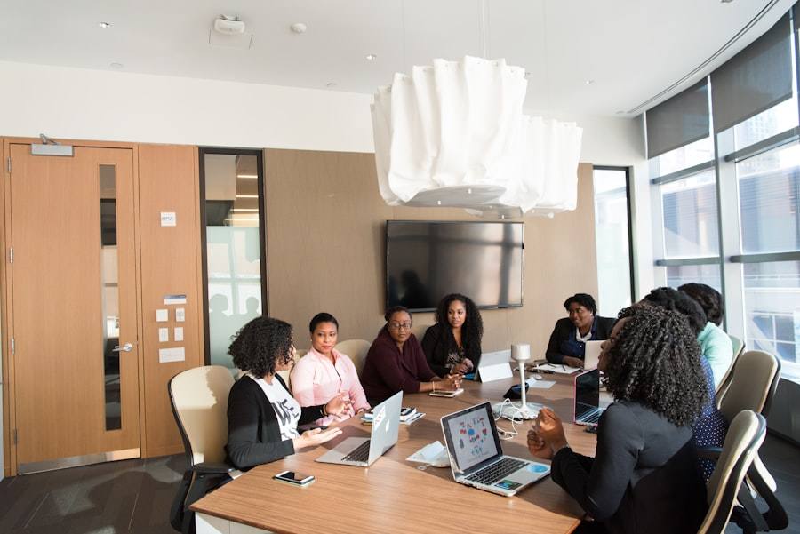Several women meeting around a conference table with laptops