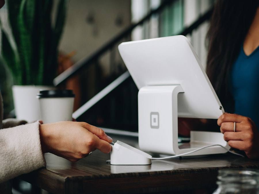 A customer paying with a card reader beside a white tablet register