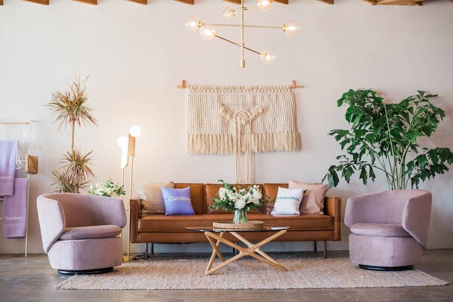 A living room with a tan leather sofa, two pink armchairs and a woven wall hanging