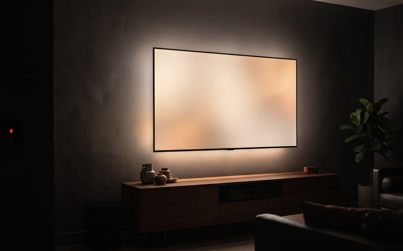 A backlit wall-mounted TV above a walnut media console in a dark living room
